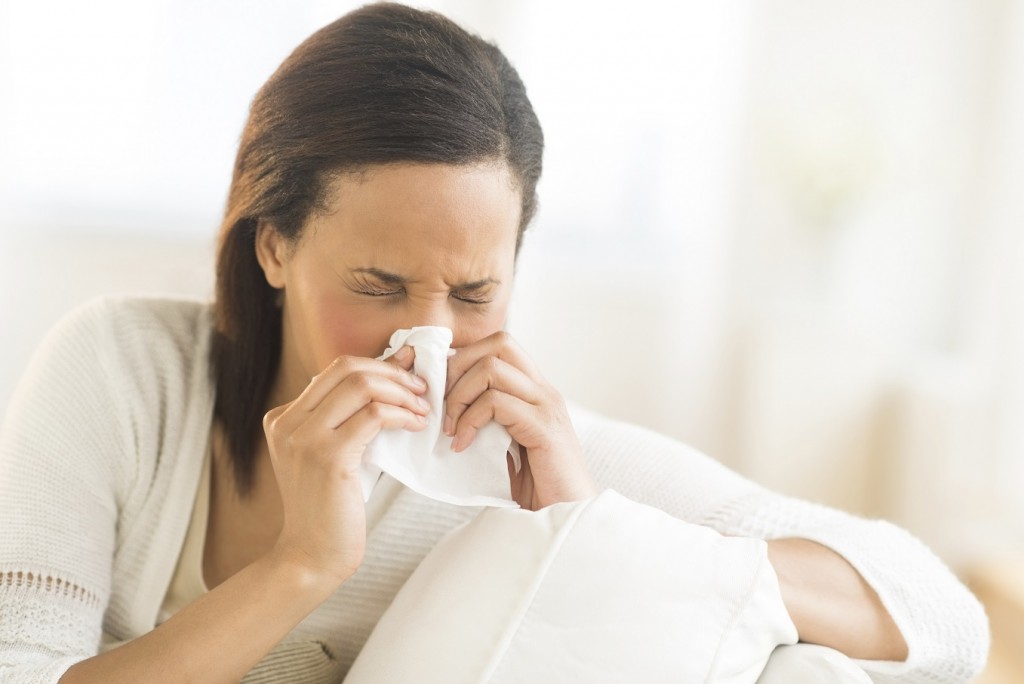 Woman Blowing Nose With Tissue At Home