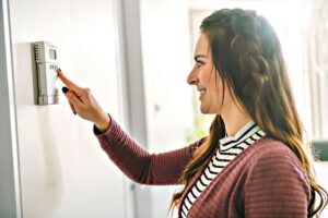 woman adjusting thermostat