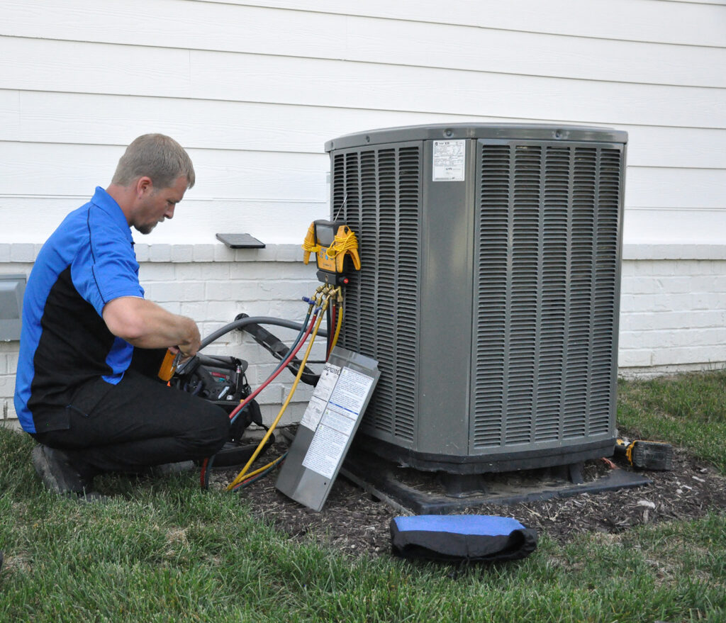 An AC tech working on an outdoor air conditioning unit at an Indianapolis home