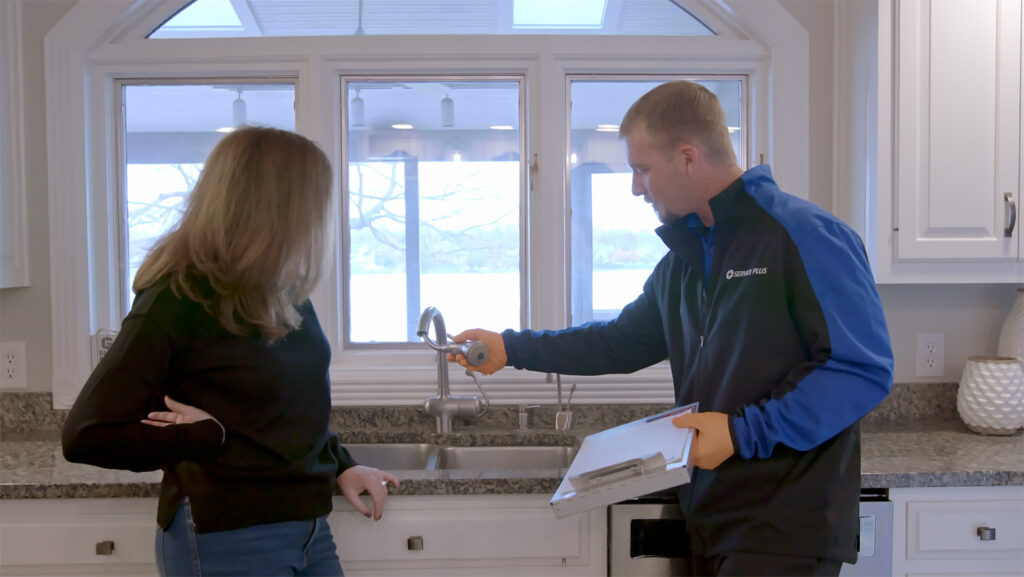 A Service Plus plumber reviewing a faucet with a customer in an Indianapolis home