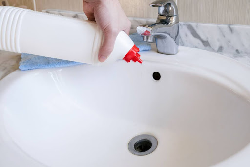 A hand pouring a drain cleaner down a sink.