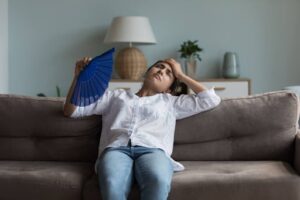 A woman fanning herself in a hot home.