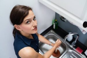 A woman plunging a clogged sink.