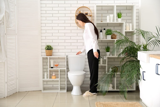 A woman flushing a toilet.